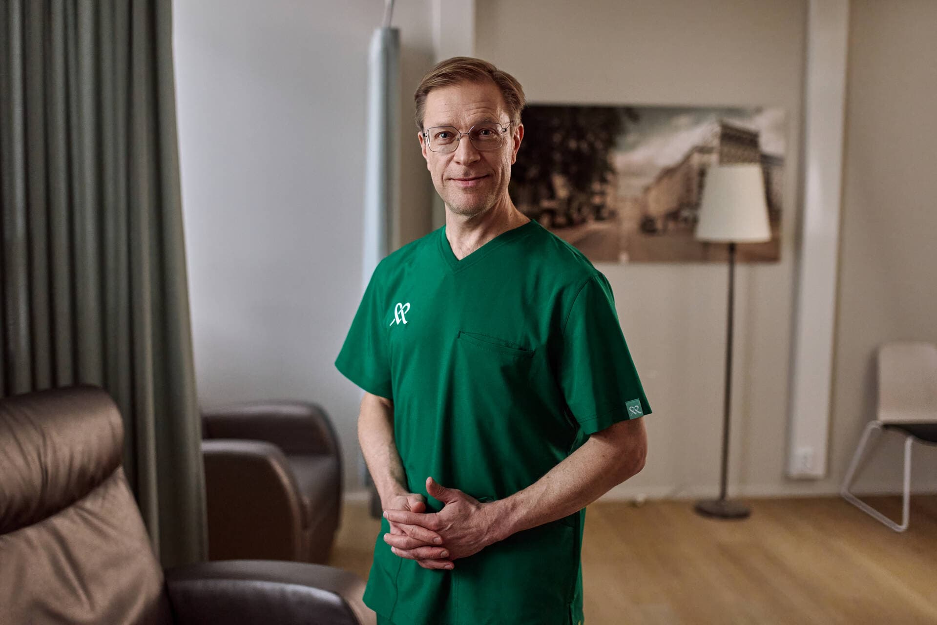 Mehiläisen kirurgi seisoo Mehiläisen sairaalan käytävällä ja hymyilee.