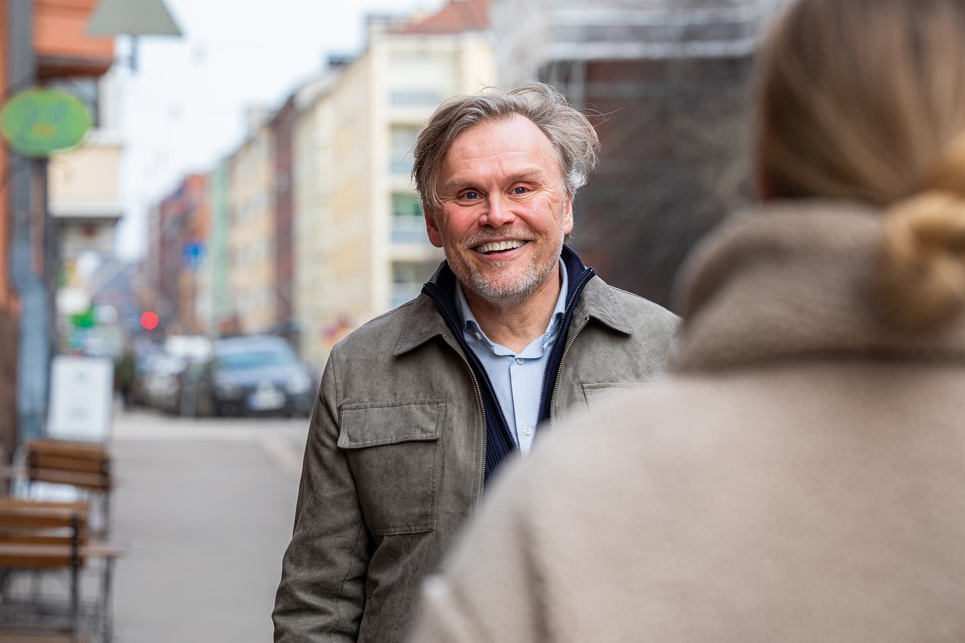 Virtsatiekivistä kärsivä keski-ikäinen mies hymyilee kadulla vastaantulijalle.